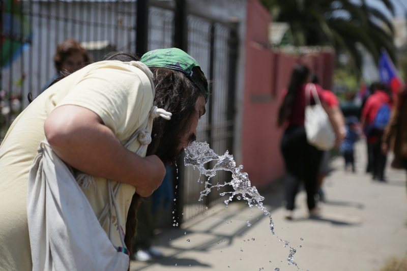 Joven tomando agua en manguera
