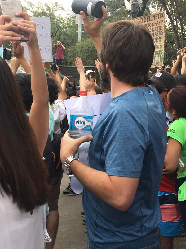 Manifestantes levantando los brazos y hombre con botella de agua
